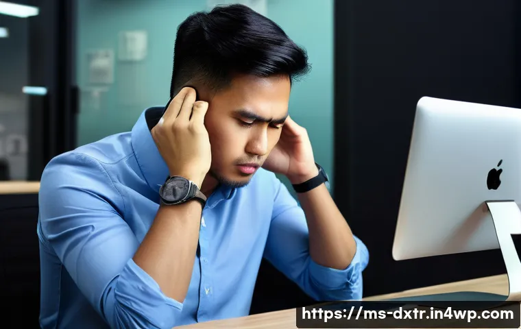 디지털 소통 방식의 변화와 번아웃 예방 - A young Malay professional in a modern office setting, sitting at a desk with multiple digital devic...